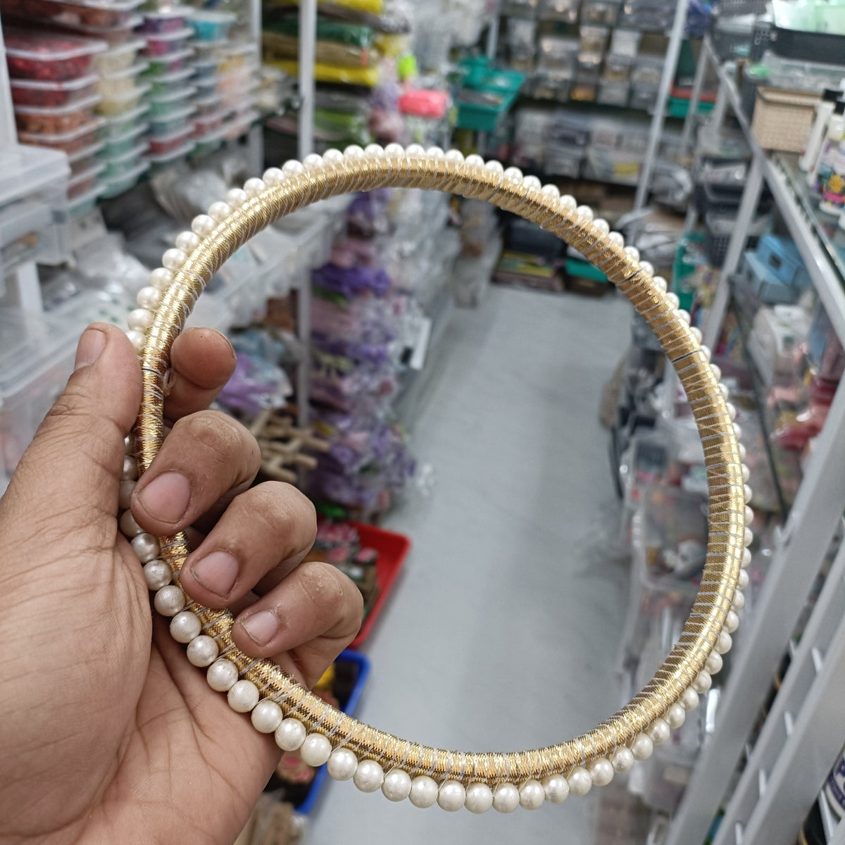 Pearl round ring with white pearls and gold-tone beaded border, angled view