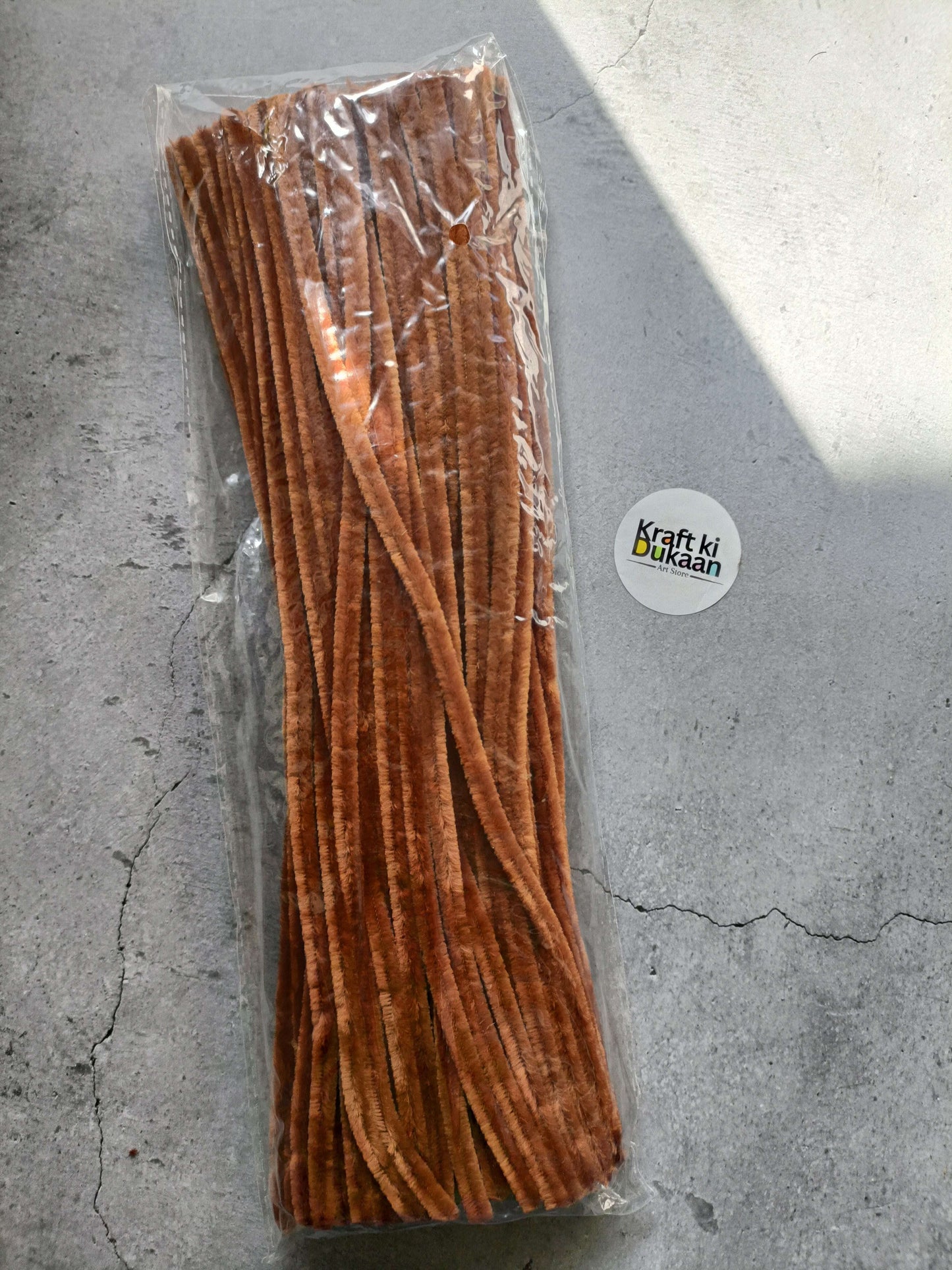 Brown pipe cleaners bundle in clear packaging, fuzzy chenille texture.