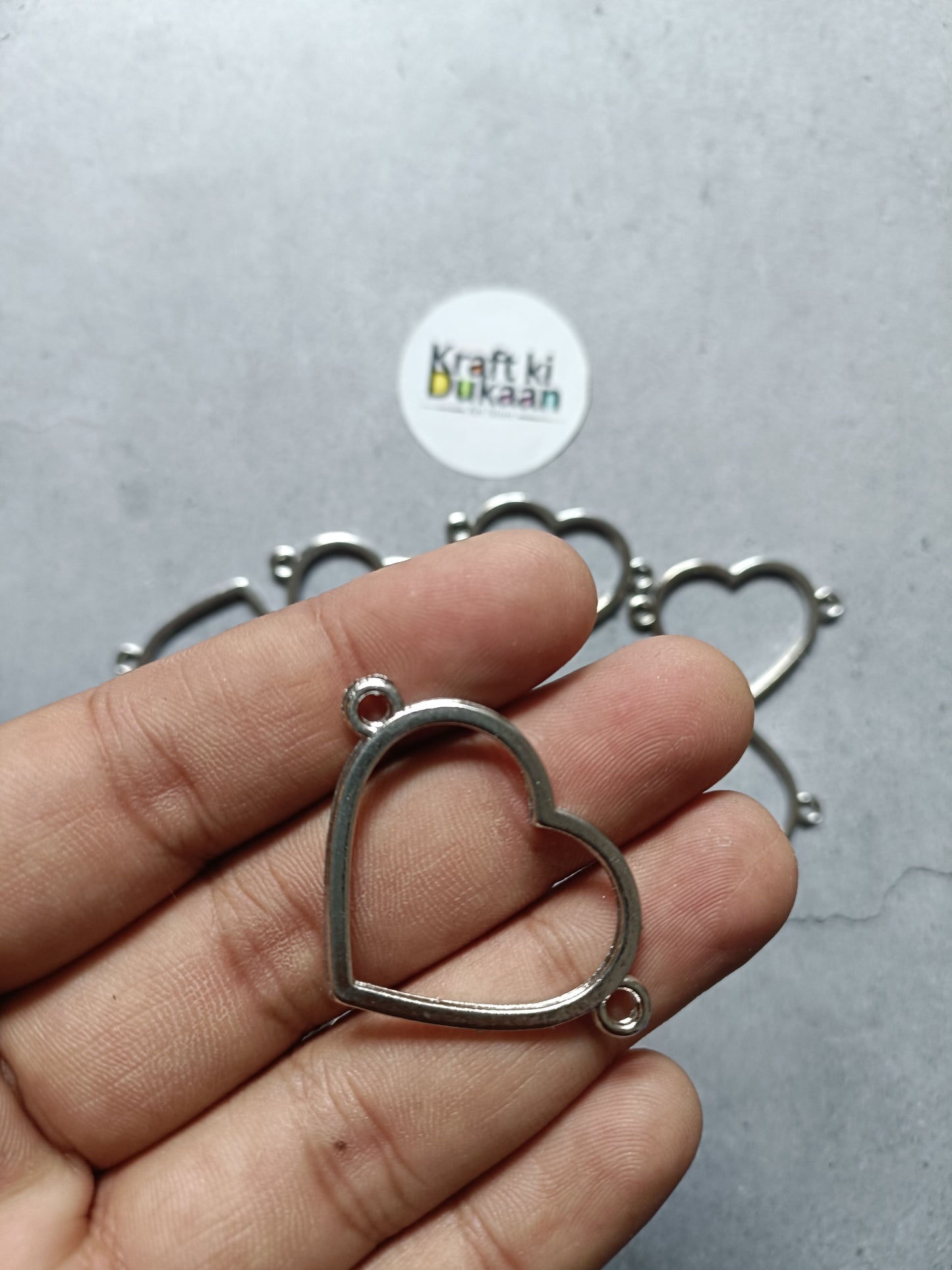 Silver-tone heart bezel bracelet with open heart frame, shown in hand