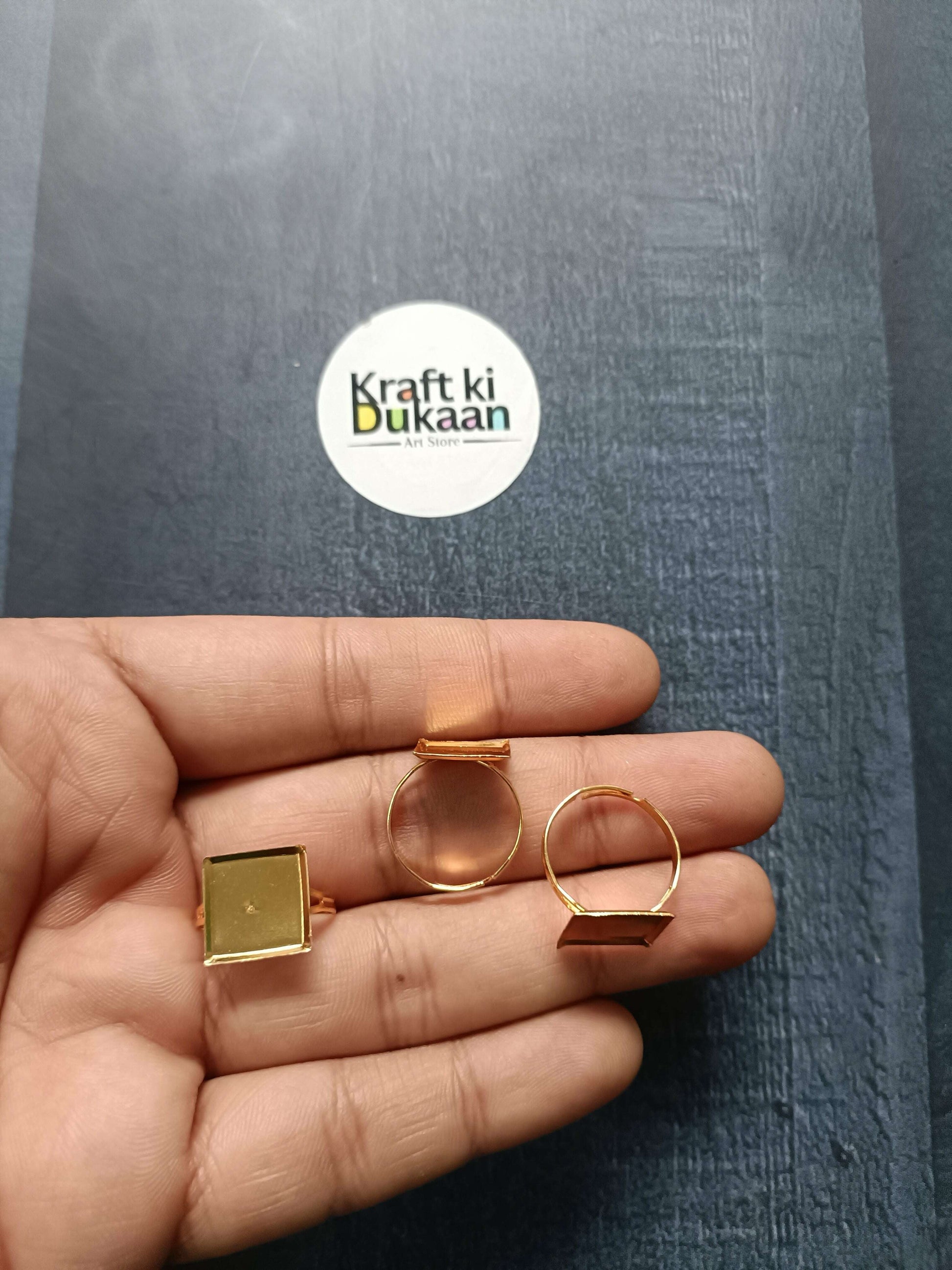 Gold-tone ring bases in hand: square and rounded bezel open bands