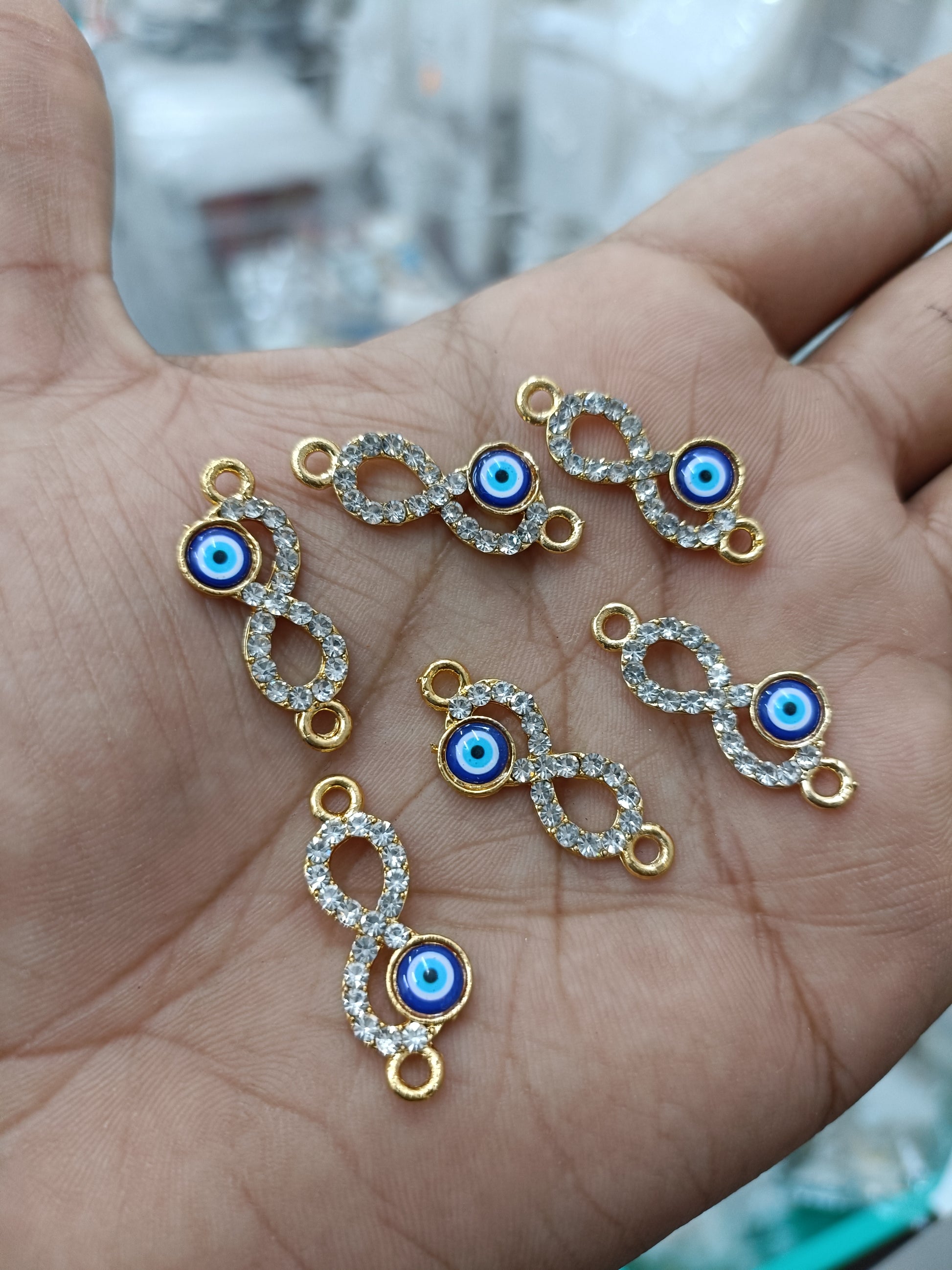 Gold-tone evil eye infinity pendants, blue enamel eye with rhinestone trim (6)