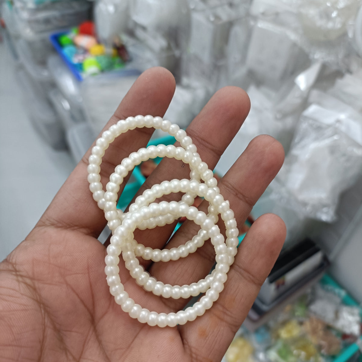 Pearl ring with a wide loop of small white beads held in a hand