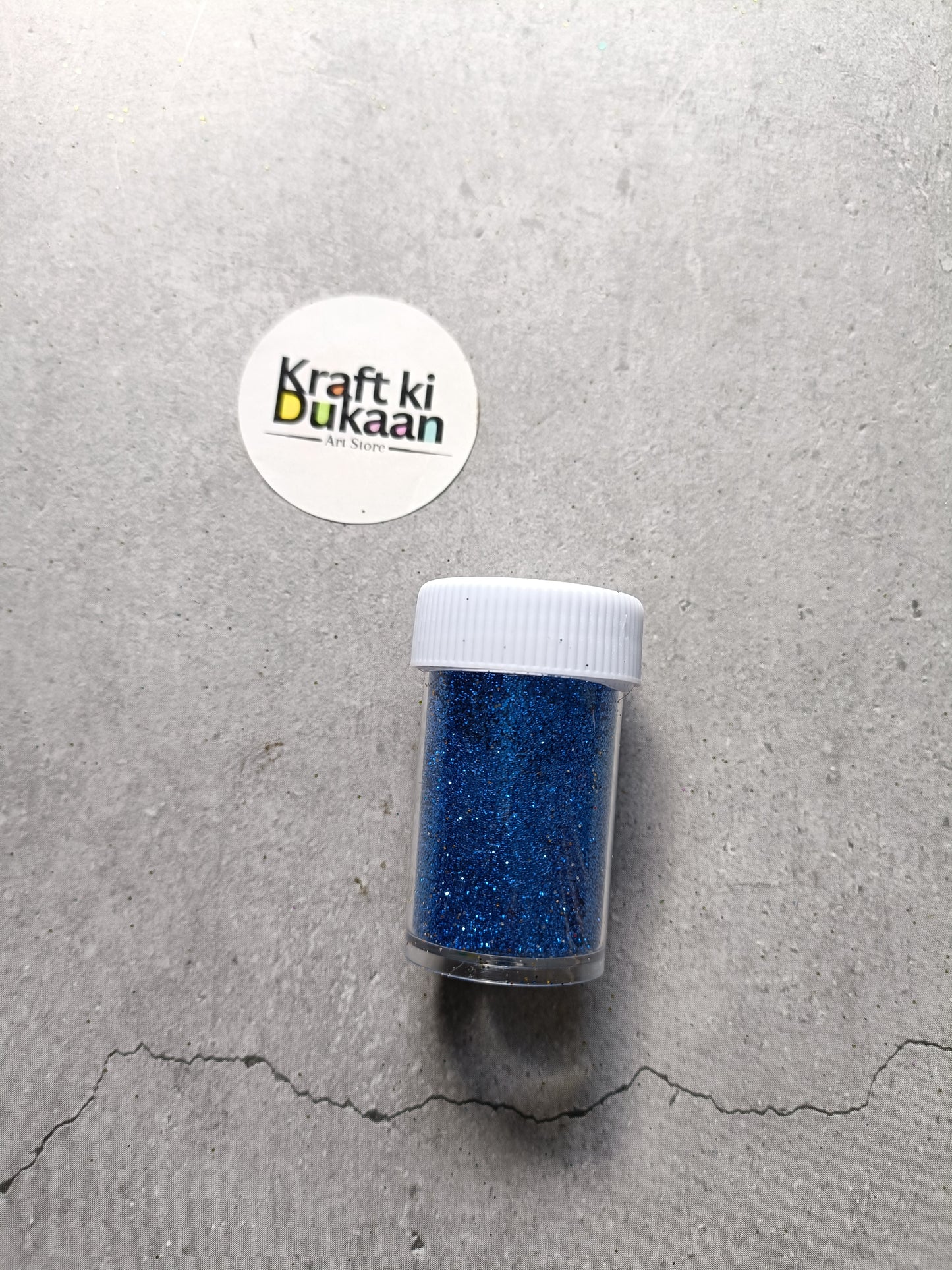 Royal blue chunky glitter powder jar with white lid.