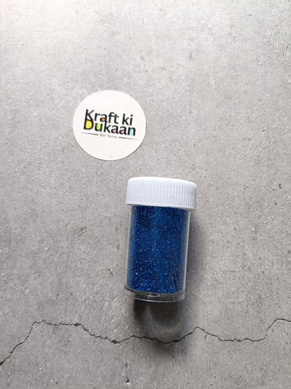 Royal blue chunky glitter powder jar with white lid.