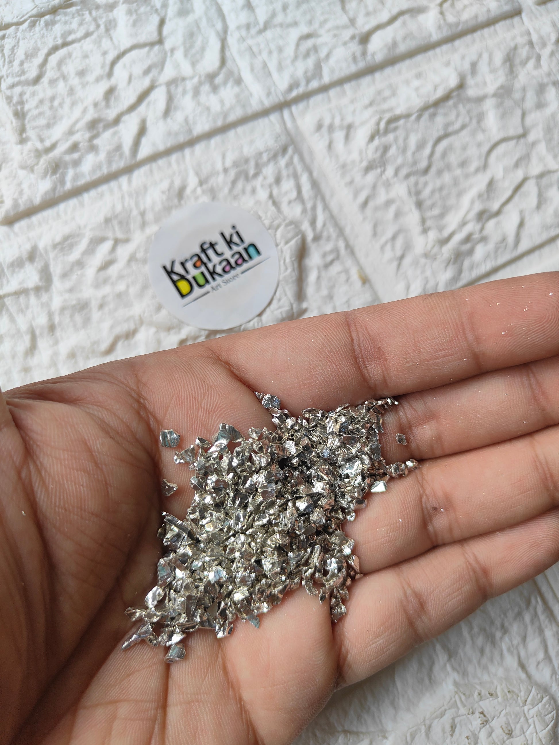 Silver stone granules, small glitter pieces for crafts, shown in palm