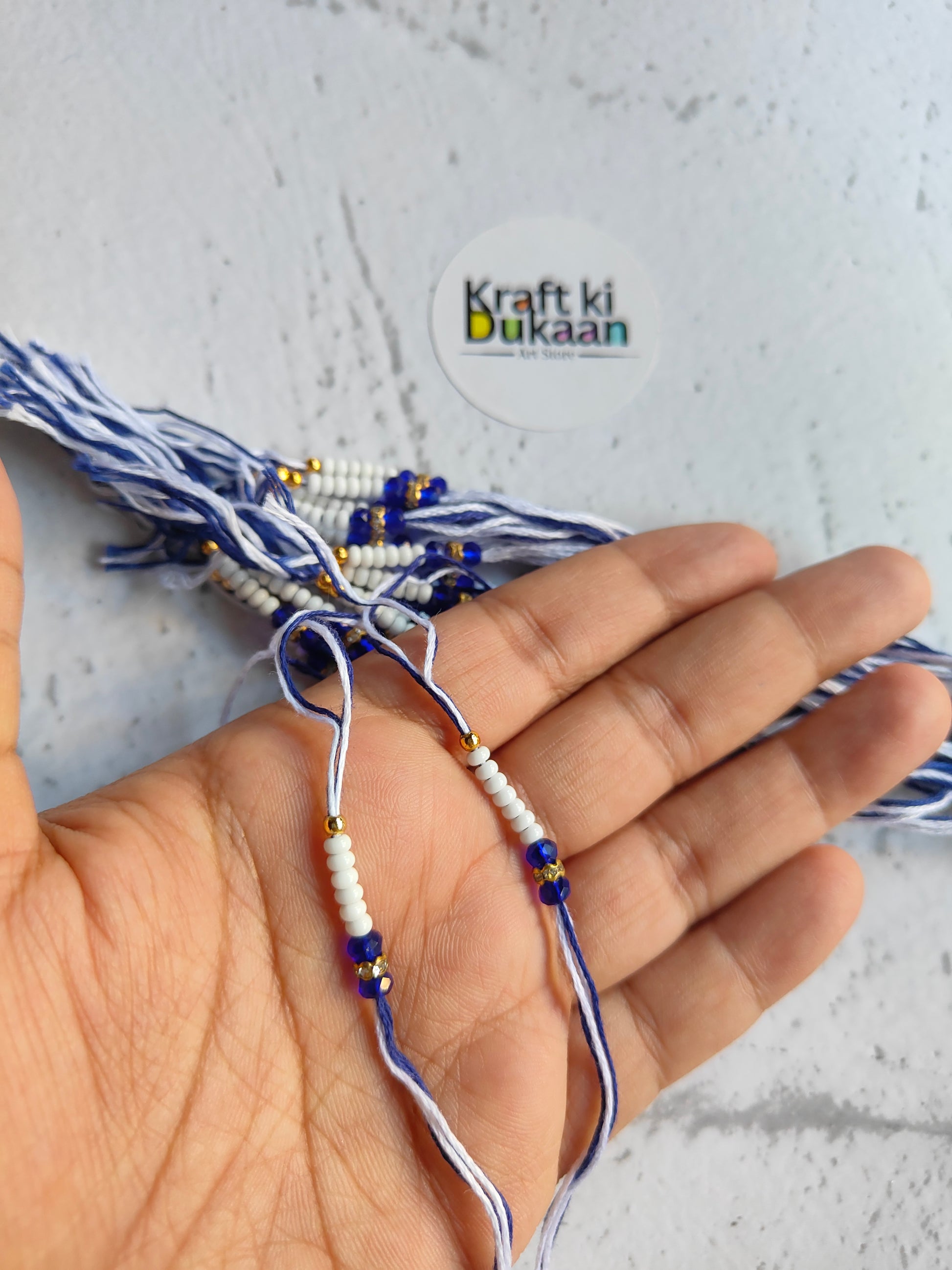 Rakhi dori threads on hand with blue braids and small white-gold beads