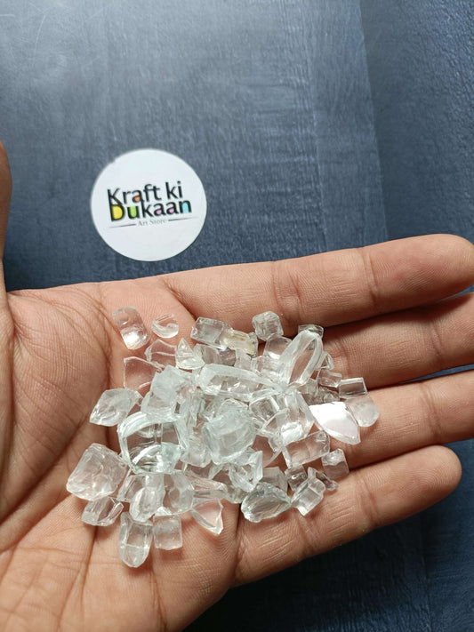Transparent crystal stones in a hand, assorted clear faceted pieces.