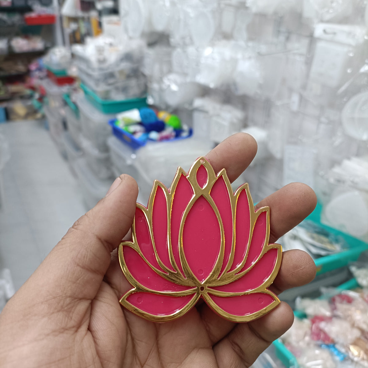 Pink-red lotus acrylic tea light holder with gold trim, shown in hand