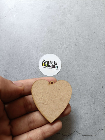 Heart-shaped MDF piece with small hole, tan brown, held in hand.