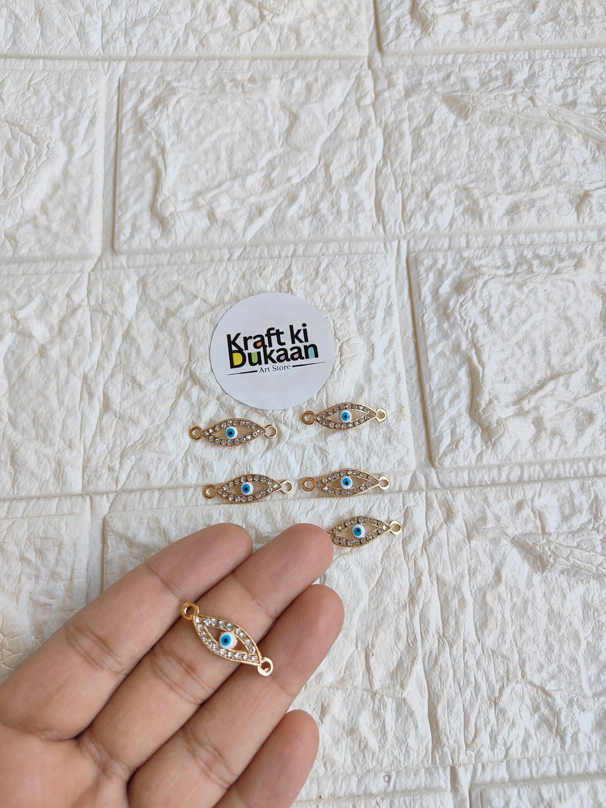 Gold-tone rakhi bracelet pendant with blue oval eye motif and small bead detailing
