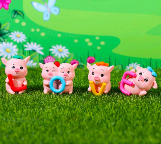 Four mini pink pig figurines with red outfit, blue ring, orange hat, and pink handle