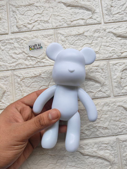 Light blue teddy bear figurine held in hand, rounded ears and face