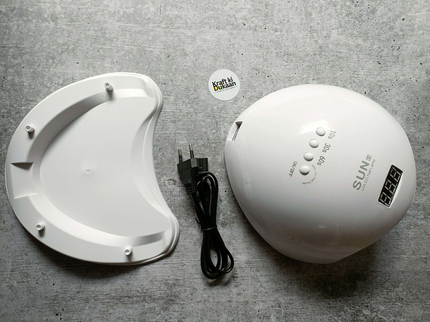 White UV LED nail lamp beside white curing base and black power cable