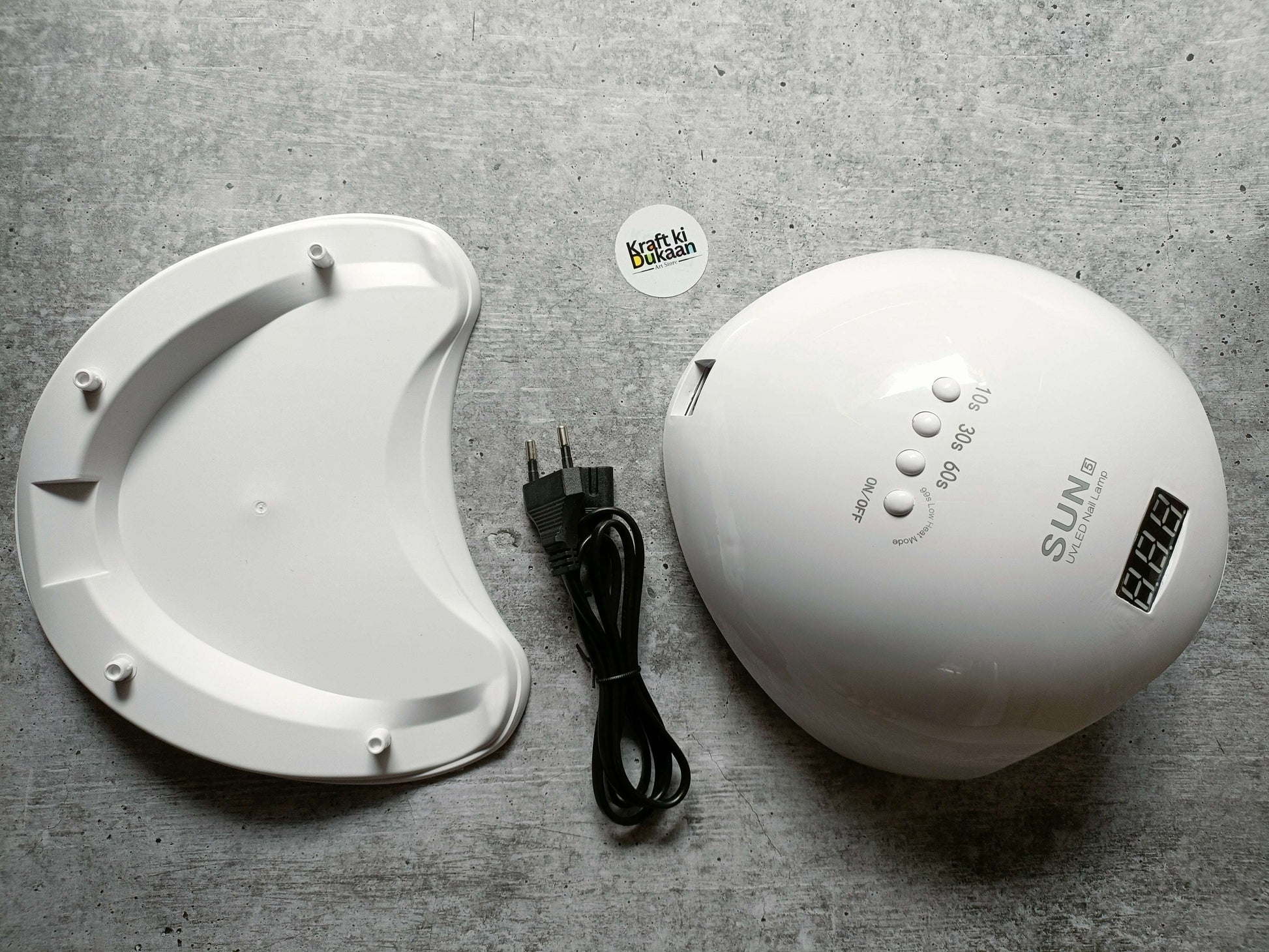 White UV LED nail lamp beside white curing base and black power cable