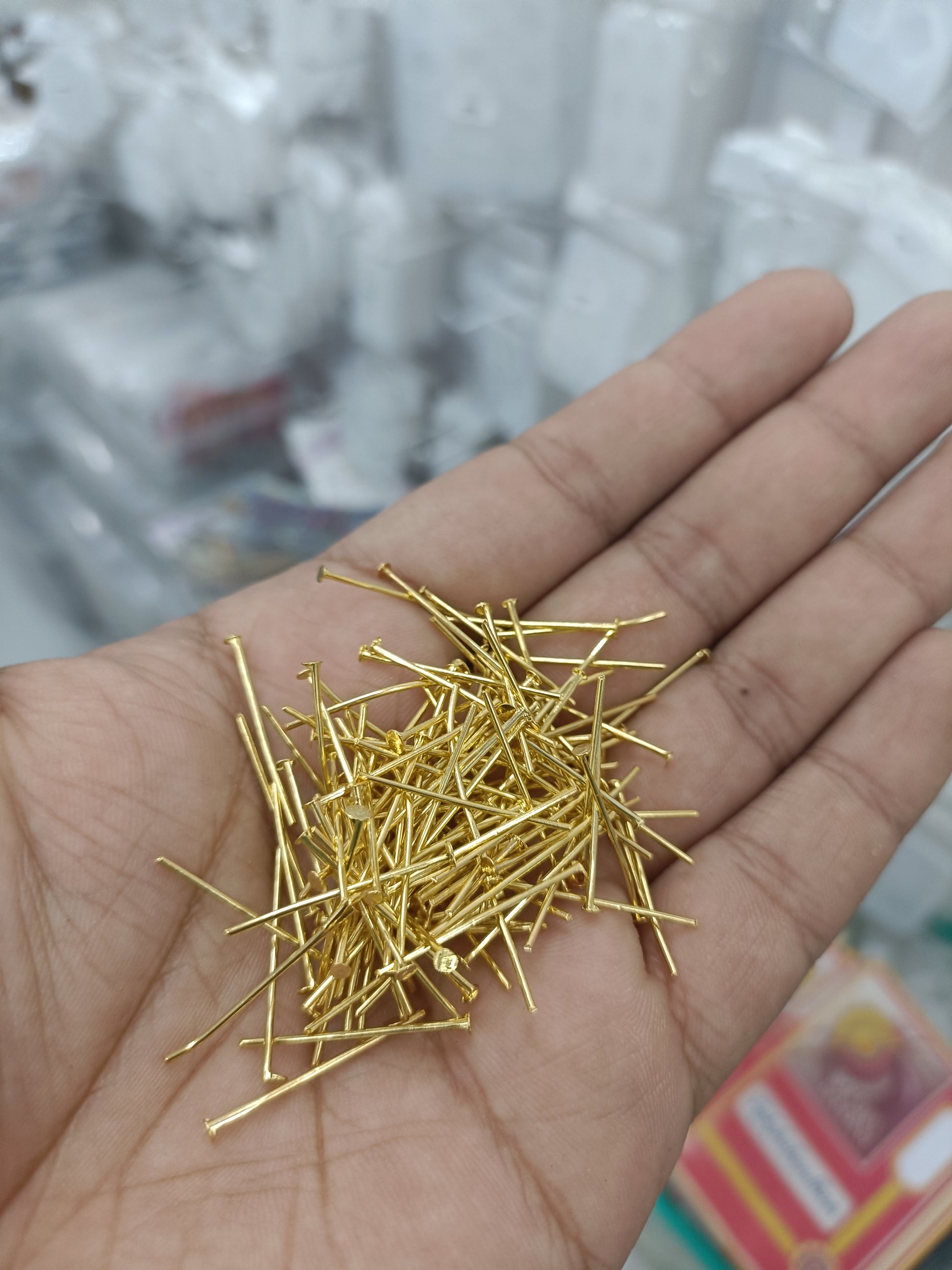 Gold jewellery head hook pins, scattered heap in palm