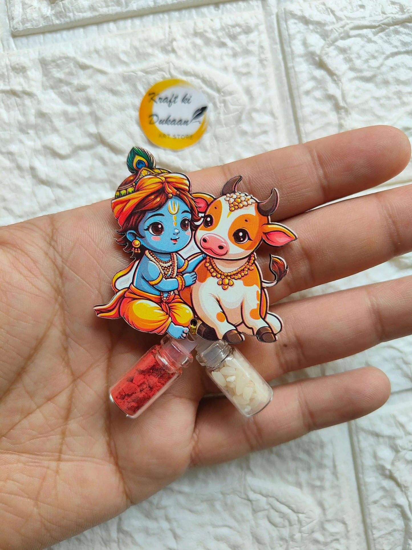 Roli Chawal Bottle Set A3 with cartoon deity and cow; two mini vials, red and cream.