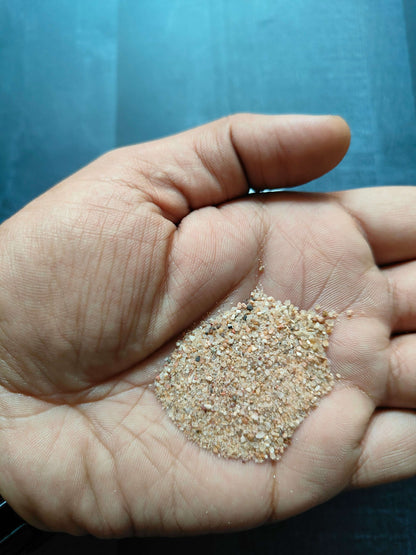 Natural sand grains in palm, light tan with mixed tiny pebbles