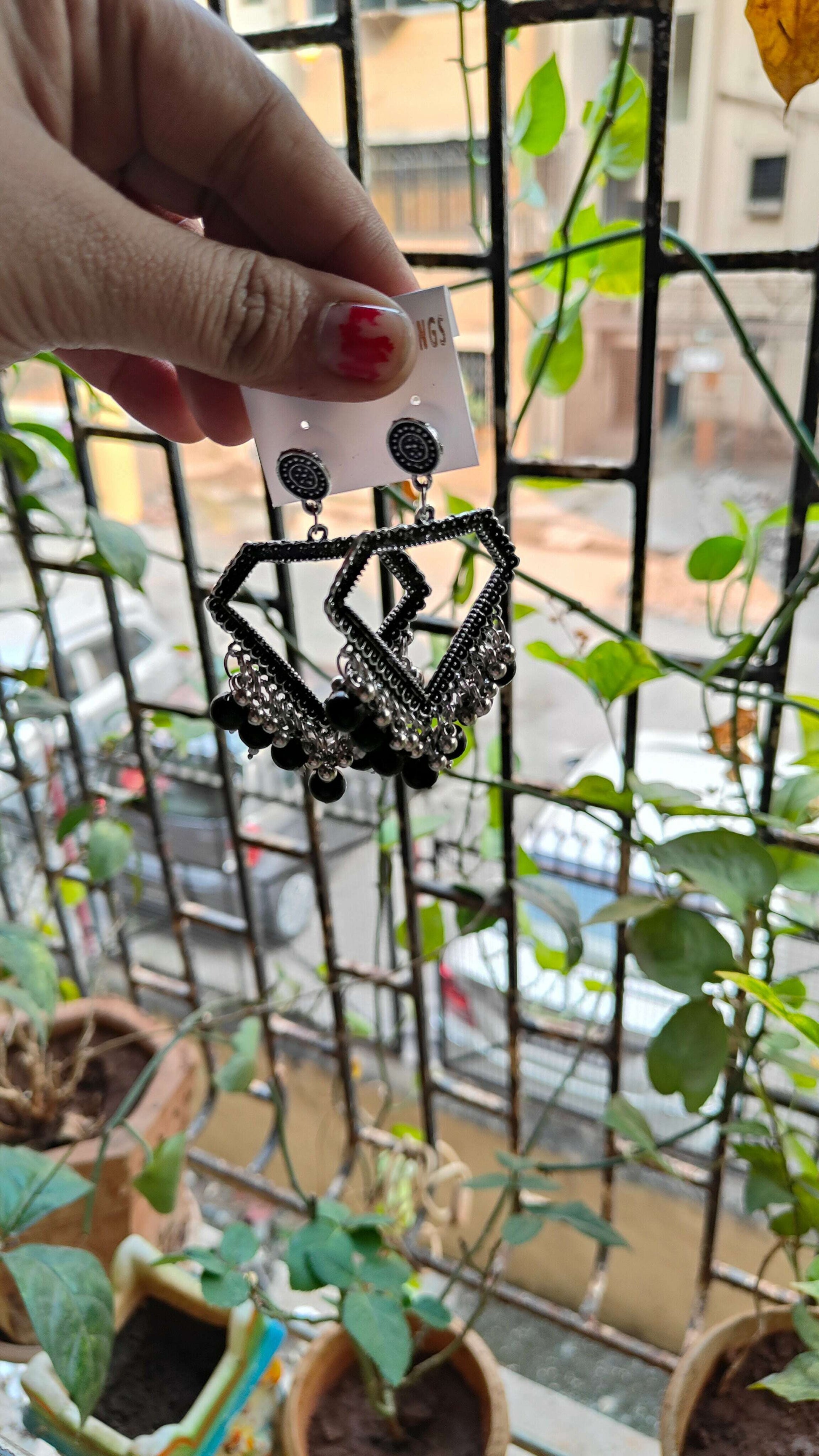 silver-jhumka-earrings-with-beads-black-held-in-hand