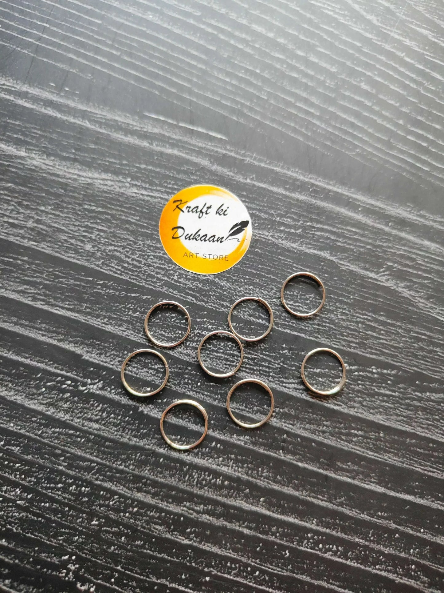 Silver circle metal rings, open loop style, arranged in a scattered group.