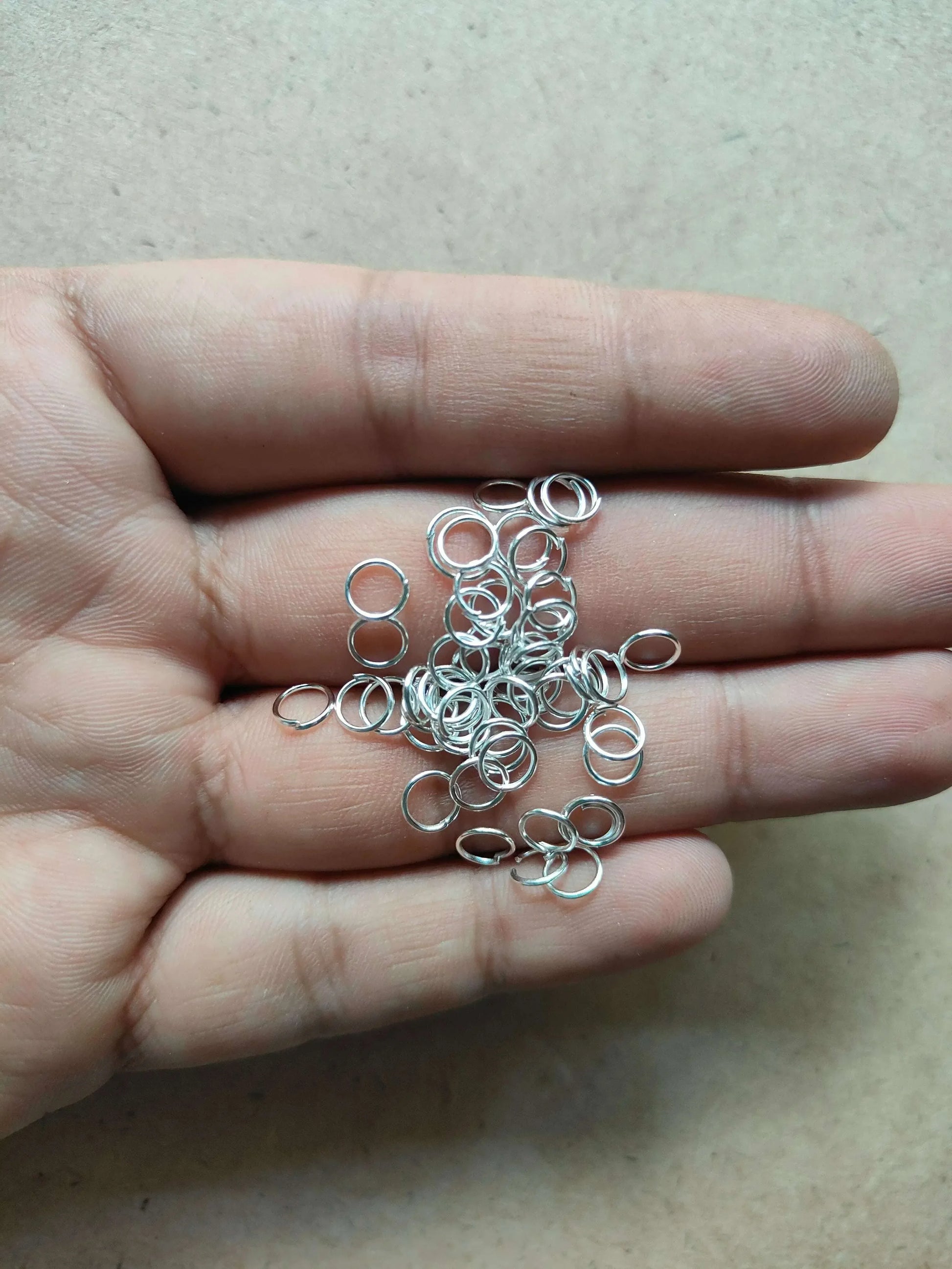 Silver-tone metal circle rings in a hand, small open loop rings.