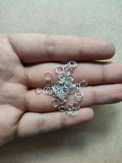 Silver-tone metal circle rings in a hand, small open loop rings.