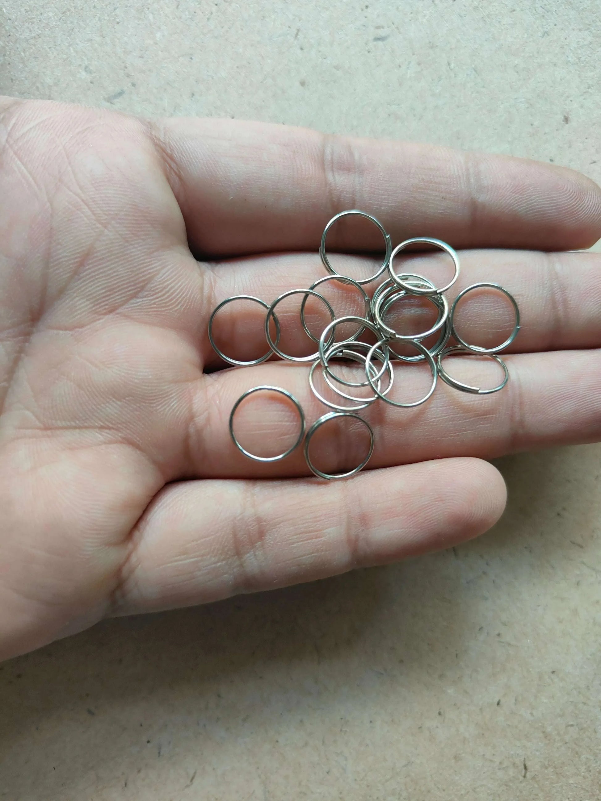 Small silver circle metal rings in hand, shiny open loops.