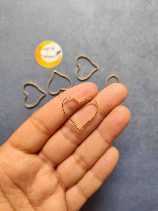 Heart bezel earring findings set—gold-tone outline heart in hand view