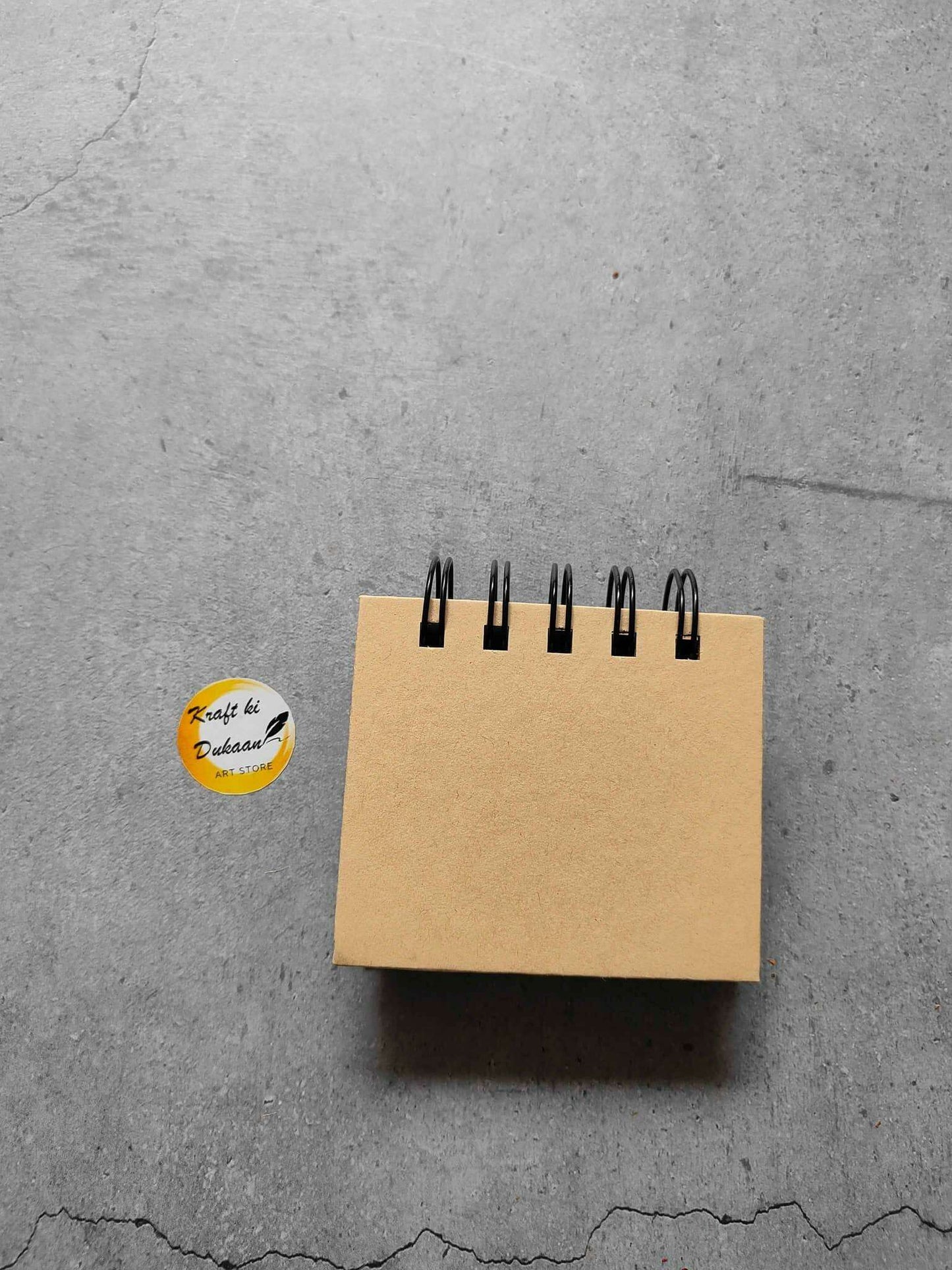 Spiral sticky note pad with kraft brown cover and black coil binder at top