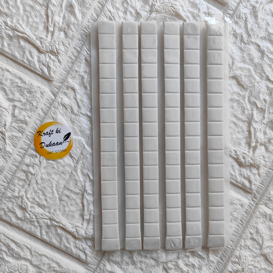 Sticky tack adhesive strips arranged on textured surface for easy mounting and craft projects