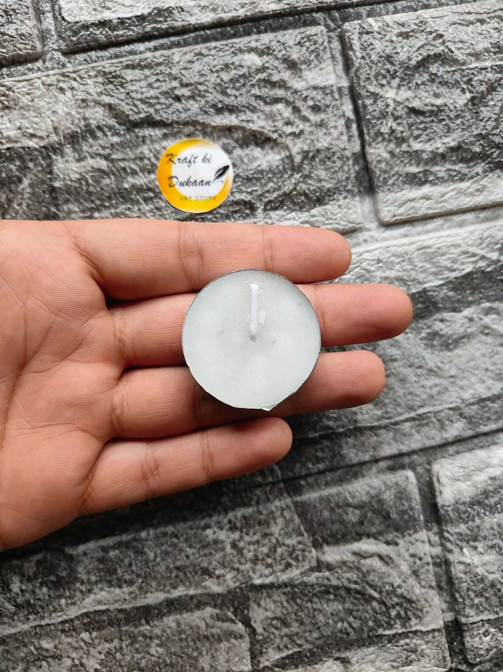 Tea light candle with white round top and visible wick