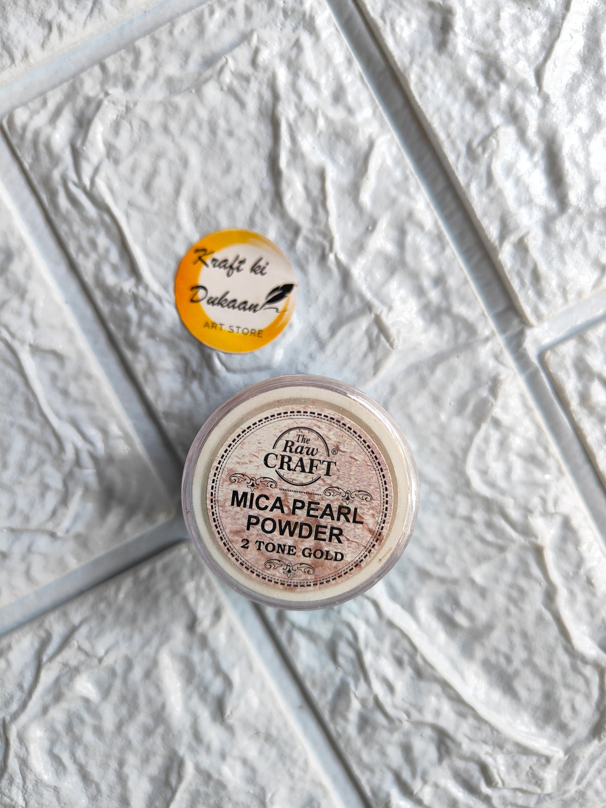 Kraft ki Dukaan MICA pearl powder for resin in 2 tone gold with a lid on a textured surface