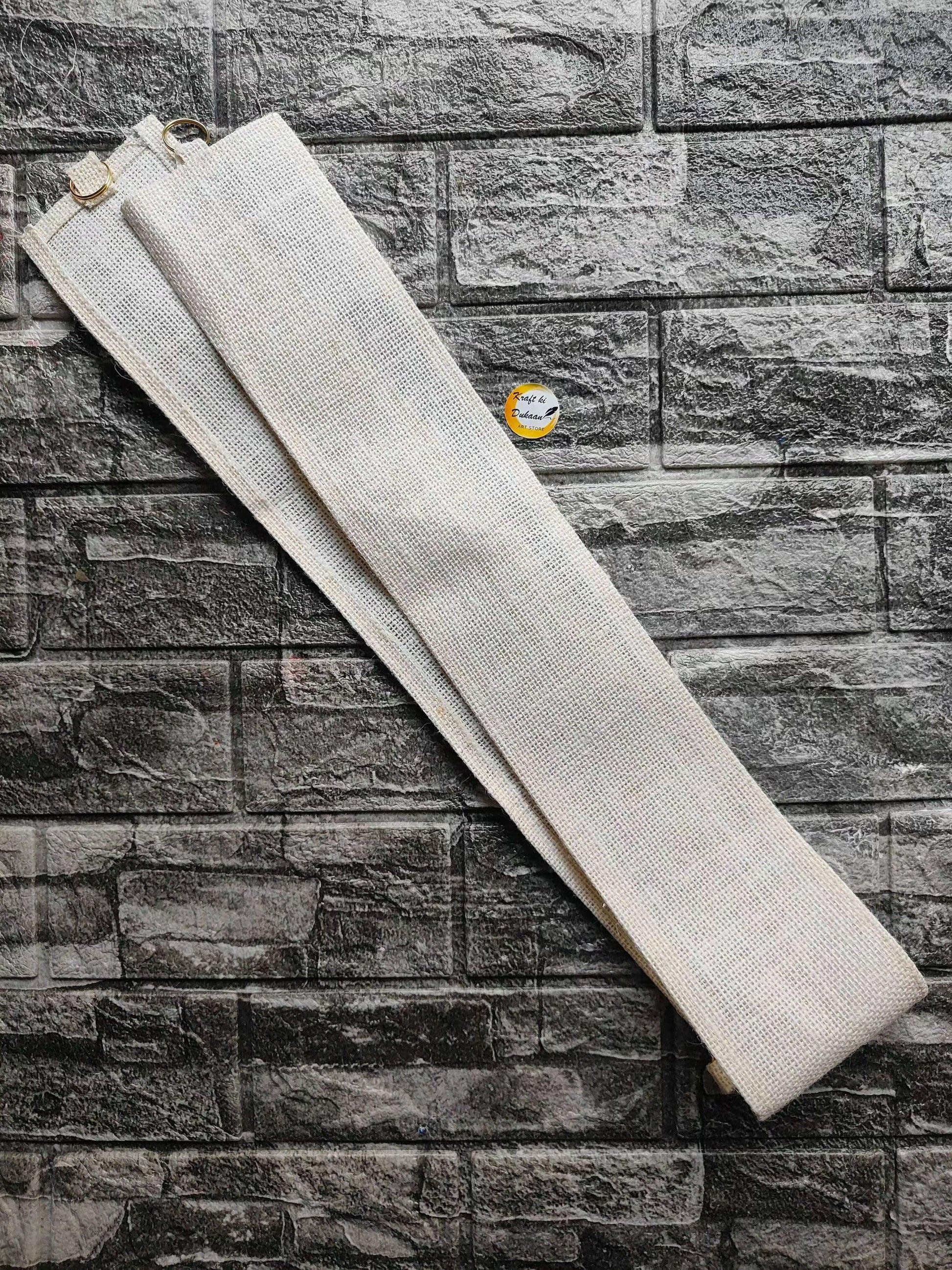Toran belt with textured white fabric strap and small metal ring at one end