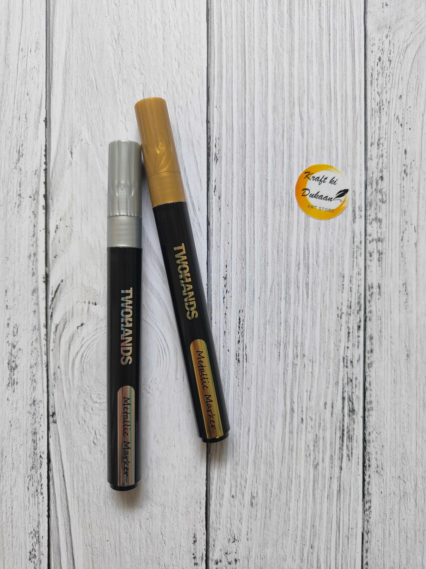 Metallic paint markers set: silver and gold tips, black bodies, capped ends.