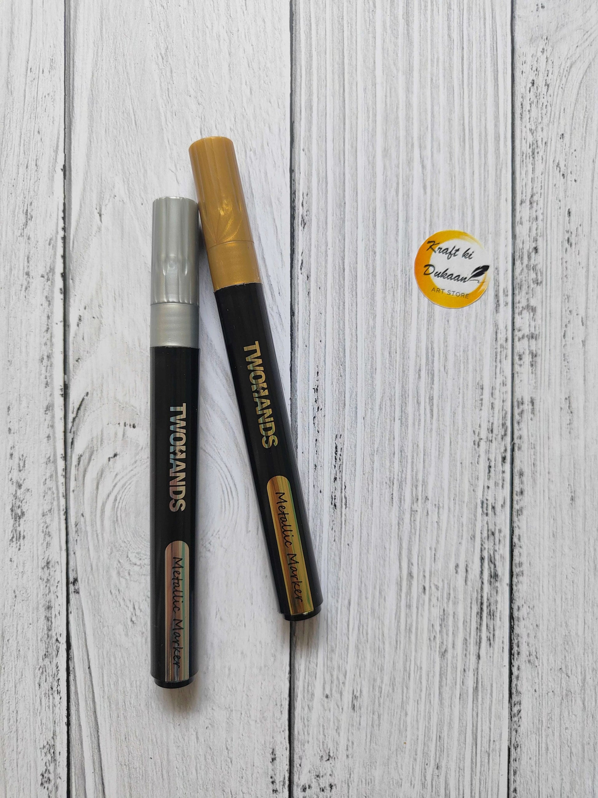 Metallic paint markers set: silver and gold tips, black bodies, capped ends.