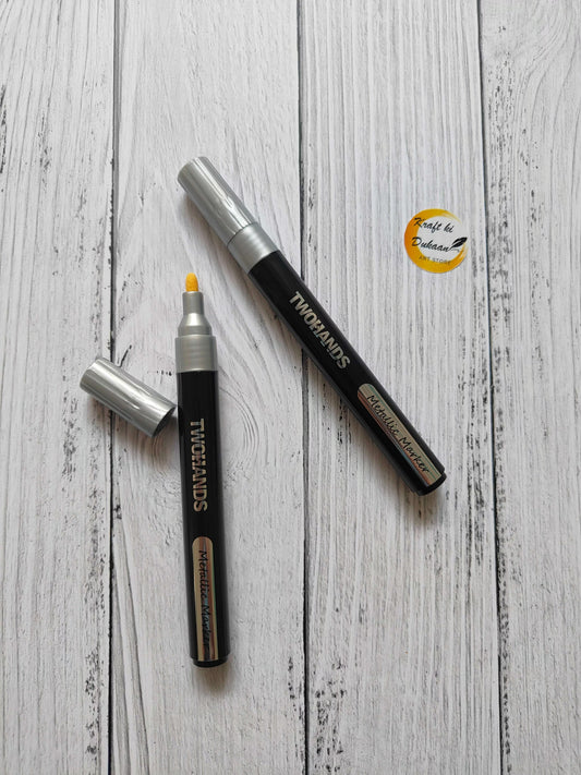 Metallic paint marker, silver tip and cap on black body.