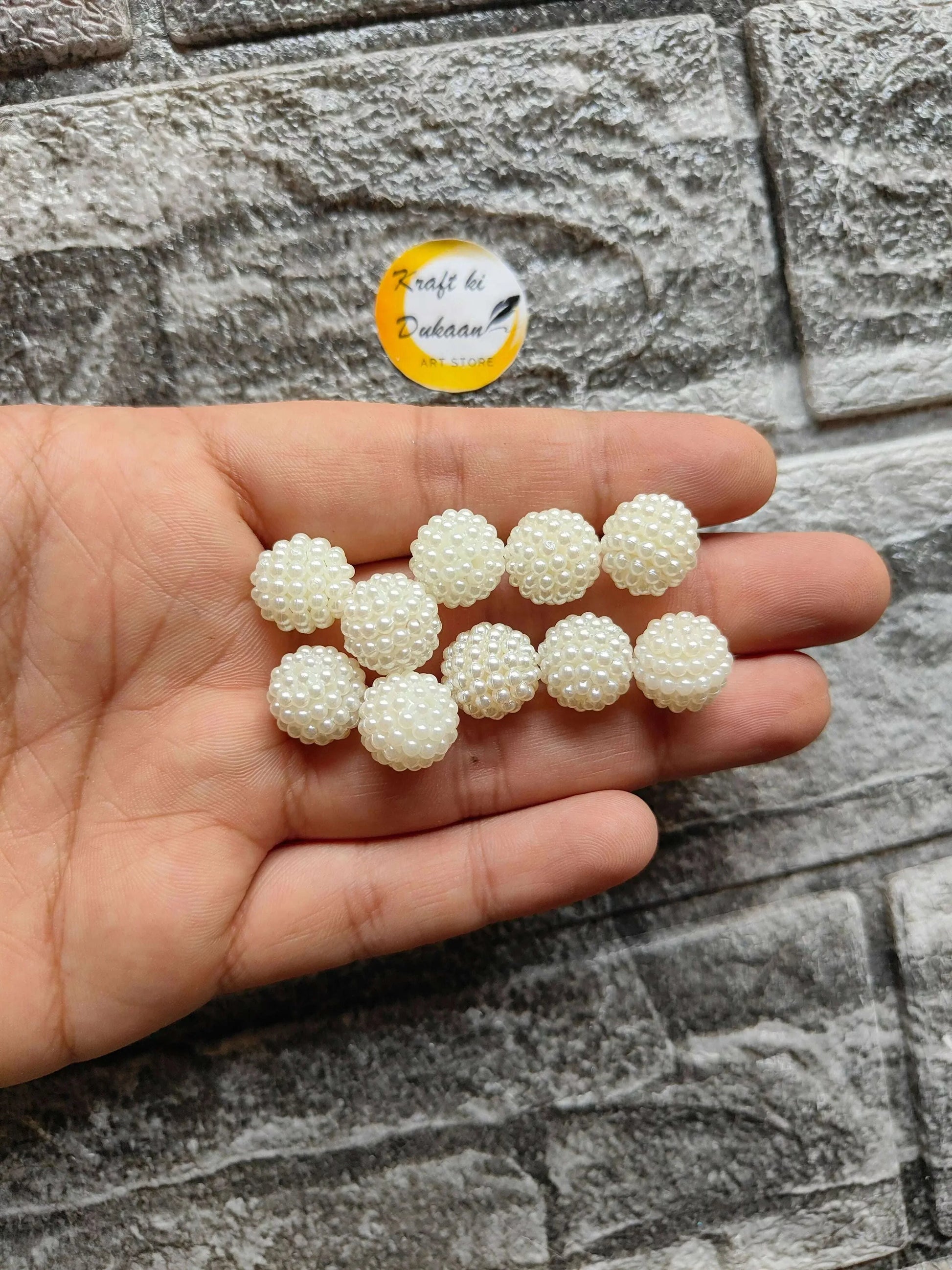 White pearl ball beads held in hand, textured beaded sphere with shine
